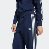 Pantalón deportivo Adidas Firebird Drop Needle de color azul marino, con las clásicas tres tiras blancas en los laterales y el logo del Trifolio bordado. Presenta un diseño de rayas verticales sutiles en relieve.