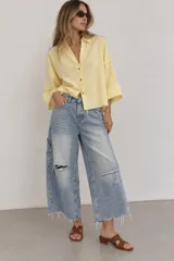 Camisa de lino blanca oversize, con cuello solapa, mangas anchas y cierre frontal con botones.