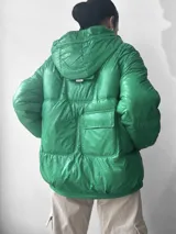 Campera puffer verde con capucha, cierre frontal con cremallera y bolsillos con solapa.
