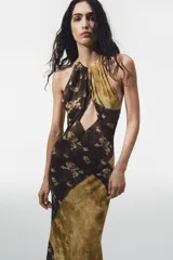 Vestido largo de viscosa con estampado floral y diseño de paneles diagonales en tonos tierra. Presenta cuello halter con cierre de botones y abertura frontal en el pecho, dejando los hombros al descubierto.