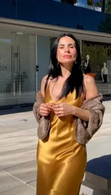 Vestido largo tipo slip dress de satén dorado, con escote en V, breteles finos y corte al bies que se ajusta suavemente a la figura.