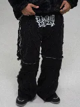 Jean baggy fit color negro con diseño de paneles unidos por cierres, permitiendo convertirlo en bermuda. Presenta bordes deshilachados y estampa serigráfica en la parte superior.