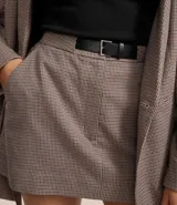 Short pollera de corte sastrero, color gris con estampado de cuadros. Presenta cintura fija, cierre con cremallera, bolsillos y cinturón de poliuretano.