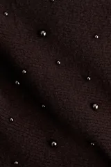 Top strapless de punto color marrón oscuro, con ajuste entallado y peplum acampanado en el ruedo. Presenta cuentas metálicas decorativas distribuidas por toda la prenda y borde interno de silicona en el escote para mayor sujeción.