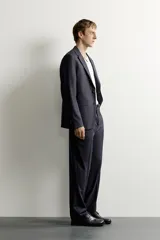 Blazer de corte relaxed fit confeccionado en tejido con lana, con solapas de muesca, manga larga con botones en los puños, bolsillos con solapa en la cadera, un bolsillo de vivo en el pecho y cierre frontal con dos botones.