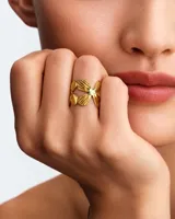 Anillo de acero dorado con diseño abierto de hojas entrelazadas.