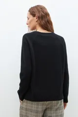 Sweater de punto en color celeste, con cuello redondo, mangas largas y puños acanalados. Presenta un diseño de corte holgado con costuras verticales decorativas en el frente.