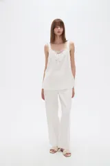Musculosa blanca de viscosa con breteles anchos, cuello en V y detalle de lazo frontal.