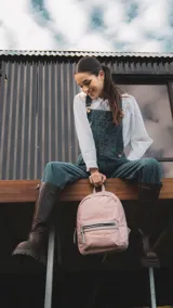 Mochila mediana color rosa, de nylon con detalles en símil cuero en el bolsillo frontal. Tiene asa de mano y correas regulables.