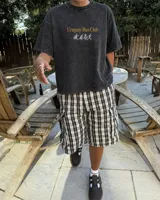 Remera marrón oversize con cuello redondo y mangas cortas. Estampado frontal con el texto "Uruguay Run Club" en celeste y siluetas blancas de personas corriendo.