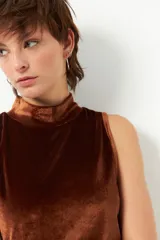 Top sin mangas de cuello alto confeccionado en terciopelo con acabado brillante.