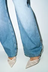 Zapato de tacón destalonado color beige, con cuerpo de tejido perforado, escote en pico, tira elástica trasera, tacón alto fino y acabado en punta.