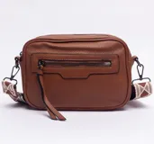 Bandolera de cuero sintético color marrón con textura granulada, cierre frontal con tirador largo y correa ajustable con diseño geométrico.