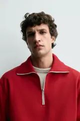 Sudadera de corte regular fit color rojo, con cuello subido y cierre frontal de cremallera. Presenta mangas largas y acabados en rib en puños y ruedo.