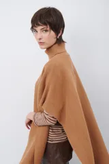 Poncho de tejido de punto color caramelo con cuello alto y diseño holgado sin mangas.