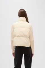 Campera híbrida con cuerpo delantero acolchado tipo puffer y mangas de tejido de punto acanalado con cuello alto. Presenta un diseño corto y holgado con cierre frontal oculto.