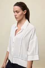 Camisa de calce relajado color celeste, con mangas 3/4, cuello clásico y cierre frontal con botones. Presenta detalles calados en el frente y en las mangas que aportan un acabado delicado al diseño.