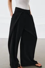 Pantalón de tiro medio de la ZW Collection, color negro, con diseño de pierna ancha (wide leg) y detalle de pliegues en la parte delantera. Cuenta con bolsillos laterales ocultos y cierre frontal con cremallera, botón y ganchos metálicos.