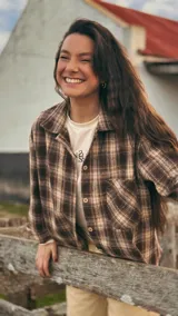 Camisa de algodón con patrón a cuadros tartán en tonos marrones y beige, de corte relajado, con cuello camisero, bolsillos frontales y cierre de botones.