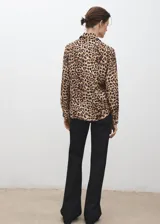 Camisa fluida de corte recto con estampado animal print de leopardo, cuello camisero, manga larga y cierre frontal con botones.