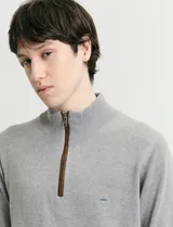 Sweater de punto azul con medio cierre frontal, cuello alto y detalles en símil nappa en la cartera del cierre y coderas.
