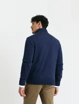 Cardigan de punto gris con cuello alto, cierre frontal de metal con doble cursor y bolsillos laterales. Presenta puños y cuello en tejido canalé.