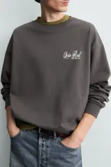 Sudadera gris oscuro de corte relaxed fit, cuello redondo y manga larga, con estampa en contraste en el pecho y acabados en rib.