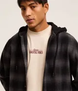 Camisa masculina de franela a cuadros en tonos grises y negros, con capucha con cordón ajustable, cierre frontal abotonado y mangas largas.