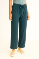 Pantalón ancho de tiro medio, color verde azulado oscuro, confeccionado en tejido acanalado (rib). Presenta cintura elástica con cordón ajustable.