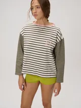 Remera manga larga de corte oversize y cuello redondo, con diseño a rayas horizontales en tonos claros y verde militar, y detalle de bordado frontal.