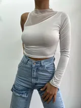 Top corto negro con una manga larga y cuello alto. Presenta un diseño asimétrico con un panel de tul transparente que cubre el hombro y parte del pecho.