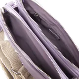 Bandolera rectangular color lila, con correa ancha de tela color crudo con diseño en espiga. Tiene dos compartimentos con cierre y un bolsillo interno con cierre.