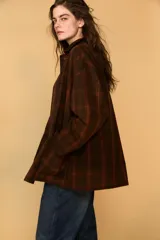 Chaqueta de mujer de la colección Zara Woman, confeccionada en algodón 100% con acabado encerado. Presenta un estampado a cuadros en tonos marrón y rojo, cuello solapa de pana, manga larga con puño y botón, bolsillos de plastrón con solapa en el delantero y cierre frontal con botones a presión.