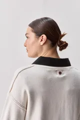 Sweater negro de tejido suave con escote redondo, mangas largas y calce relajado, con terminaciones acanaladas en cuello, puños y ruedo.