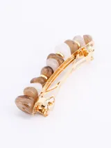 Broche para el pelo con piedras irregulares de color lila, celeste y blanco, unidas por aros dorados.