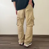 Pantalón cargo tipo parachute de color beige, con calce baggy, bolsillos laterales con solapa y cordones ajustables en los tobillos.