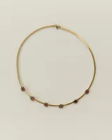 Gargantilla de cadena tipo omega en color dorado con dijes de estrellas pequeñas en acrílico marrón distribuidos a lo largo de la pieza.