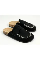 Zueco slip-on con estampado de vaca en blanco y negro, suela plana y detalle de costuras en el empeine.