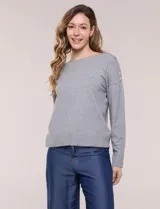 Buzo de punto fino color gris, de calce relajado, escote redondo amplio y canesú con textura acanalada. Cuenta con apliques de tachas metálicas doradas en la línea del hombro, mangas largas de hombro caído y puños y ruedo acanalados.