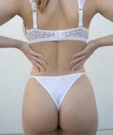 Tanga colaless color nude de lycra y puntilla elastizada con tiras finas y moños en los laterales.