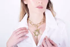 Collar dorado con cadena de eslabones gruesos y dije de sol con puntas.