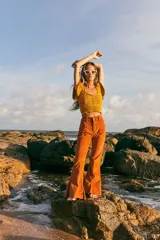 Top tejido de punto color naranja con destellos de lurex, escote redondo y mangas con volados. Presenta un diseño ajustado con cintura elástica acanalada.