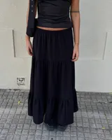Pollera larga negra de corte acampanado con diseño de volados escalonados y cintura elástica.