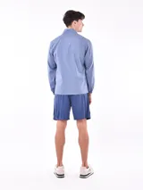 Campera deportiva azul claro, estilo cortavientos, con cuello mao y cierre frontal. Presenta puños y cintura elásticos.