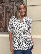 Blusa de algodón con estampado animal print de leopardo en tonos blanco y morado oscuro. Presenta cuello mao con abertura frontal y botones, y mangas cortas enrolladas con presilla.