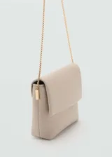 Bolso tipo bandolera de efecto piel color beige, estilo pochette, con cierre de solapa magnética y correa de cadena dorada.