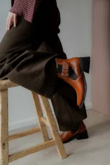 Botín negro de charol con punta cuadrada y hebilla metálica decorativa.