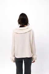 Buzo de tejido acanalado color lila, con cuello redondo decorado con dos volados y mangas largas con tres volados pequeños en los puños.