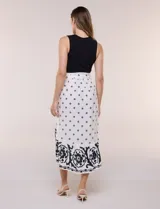Vestido midi combinado de corte fluido. Presenta un torso ajustado acanalado sin mangas, con cuello redondo y sisas clásicas. Cuenta con cintura elastizada con lazo para anudar y falda evasé con estampado floral y geométrico, finalizando con un volante en el ruedo.