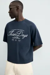 Camiseta de manga corta, cuello redondo y calce relajado, confeccionada en tejido con estructura waffle de color azul marino. Presenta estampados y bordados combinados a contraste en el delantero con texto en blanco.